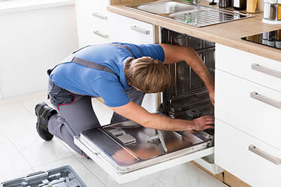 Plumber installing new dishwasher in kitchen