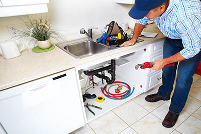 Plumber installing new appliances in kitchen